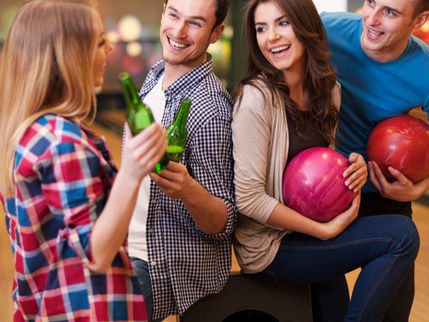 group of adults bowling and having drinks at king's entertainment