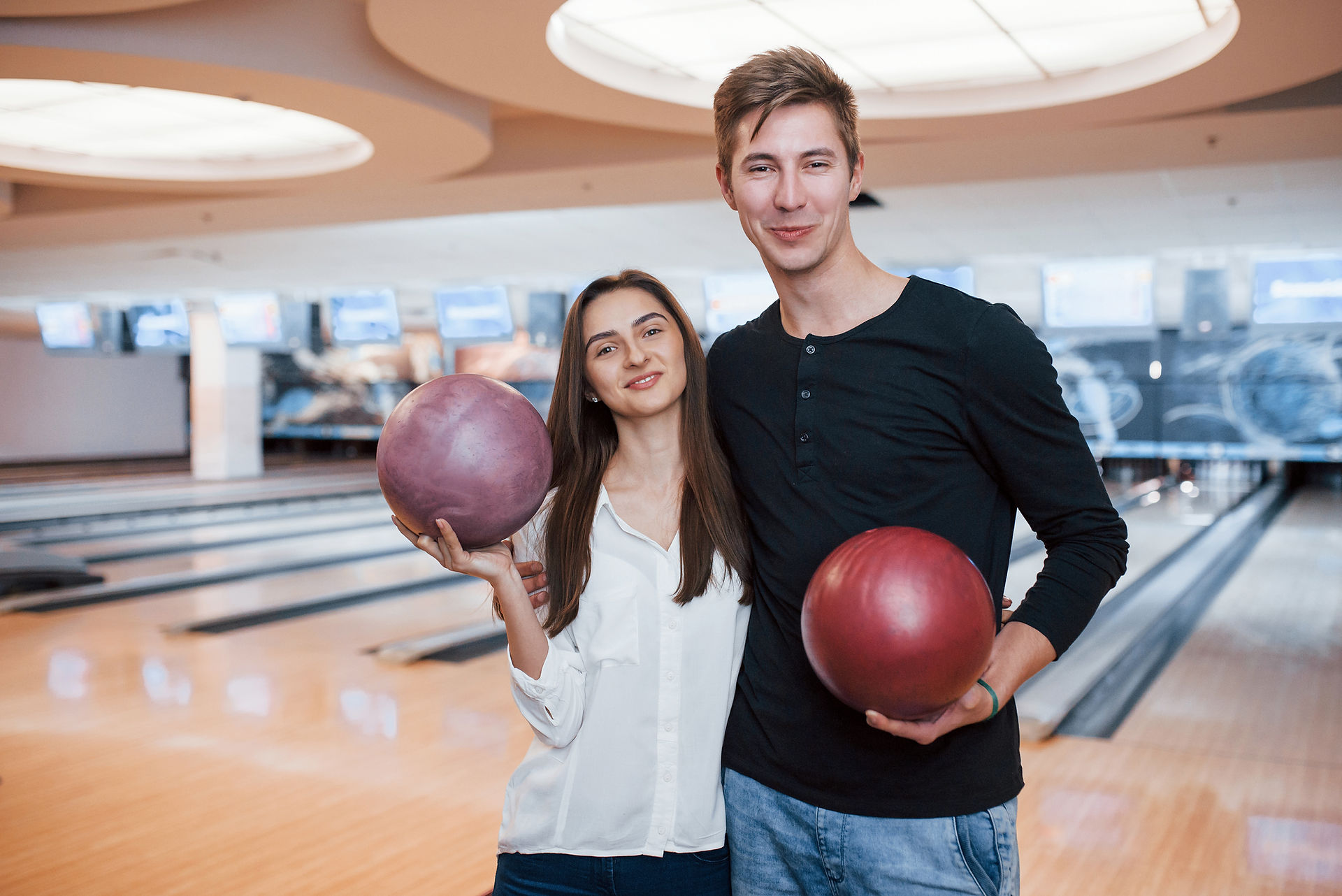 a man and woman holding bowling balls and smiling at king's entertainment 