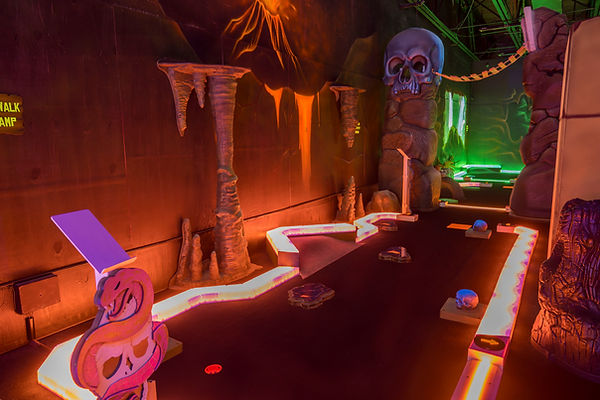 Ancient ruins blacklight mini golf at King’s Entertainment with glowing skulls, stone paths, and cave-like scenery