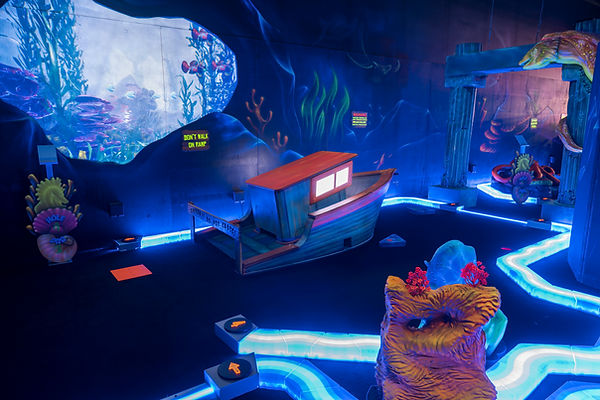 Underwater-themed glow-in-the-dark mini golf course at King’s Entertainment featuring coral reefs, shipwrecks, and sea creatures