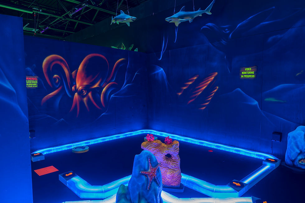 Blacklight undersea mini golf hole with jellyfish, fish, and ocean scenery
